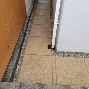 A cat sitting on the ground in front of a door.